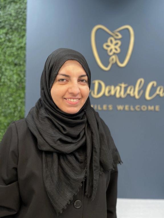a woman stands in front of a sign that says dental care