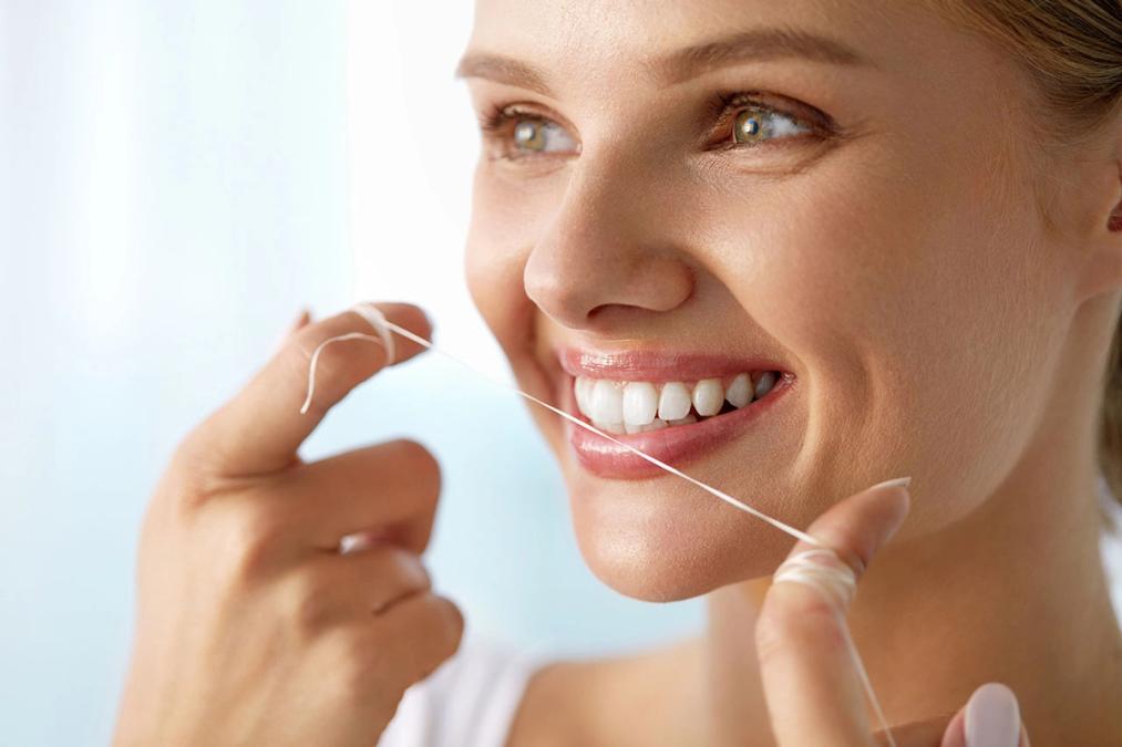 a woman is flossing her teeth with a dental floss .