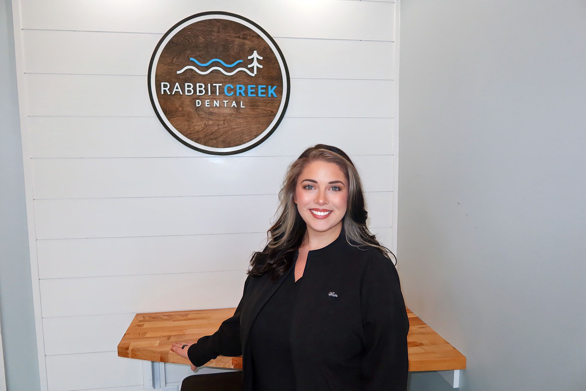 a woman is standing in front of a wooden table in a dental office .