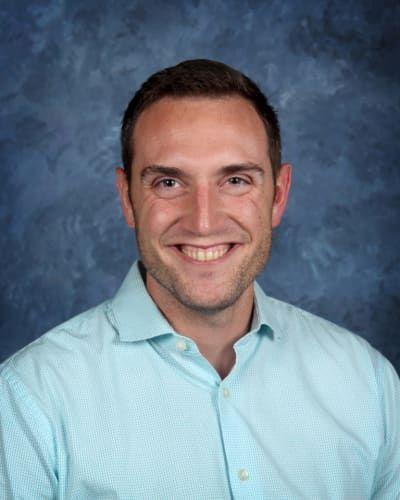 a man in a blue shirt is smiling for the camera .