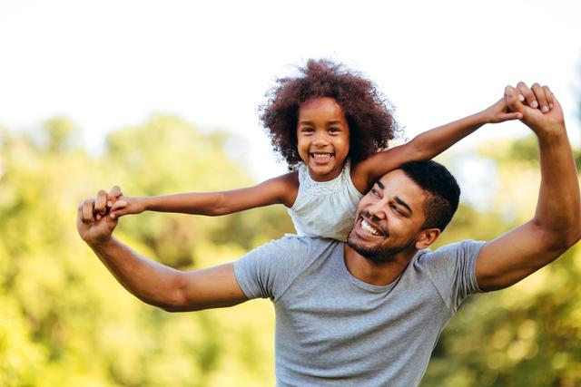 a man is carrying a little girl on his shoulders .