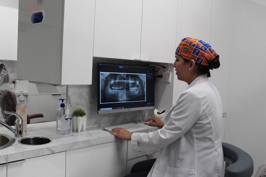 a female dentist is looking at an x-ray of a patient 's teeth on a computer screen .