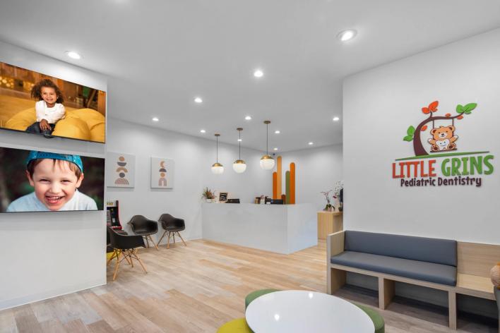 a waiting room at a pediatric dentistry with a couch and chairs .