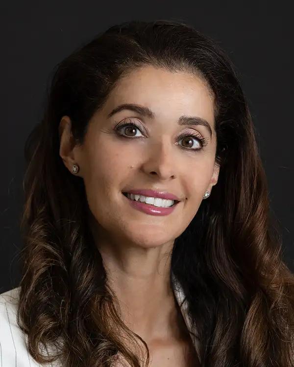 a woman with long hair and earrings is smiling for the camera .