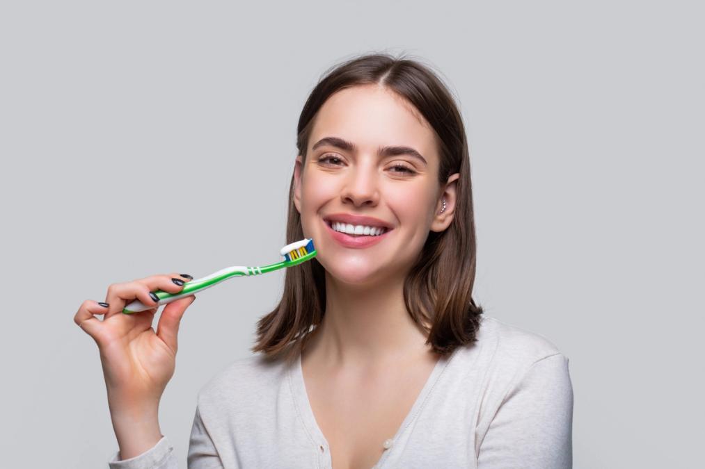 a woman is brushing her teeth with a green toothbrush .