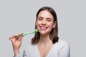 a woman is brushing her teeth with a green toothbrush .