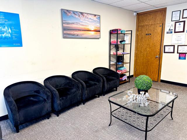 a waiting room with black chairs and a glass coffee table .