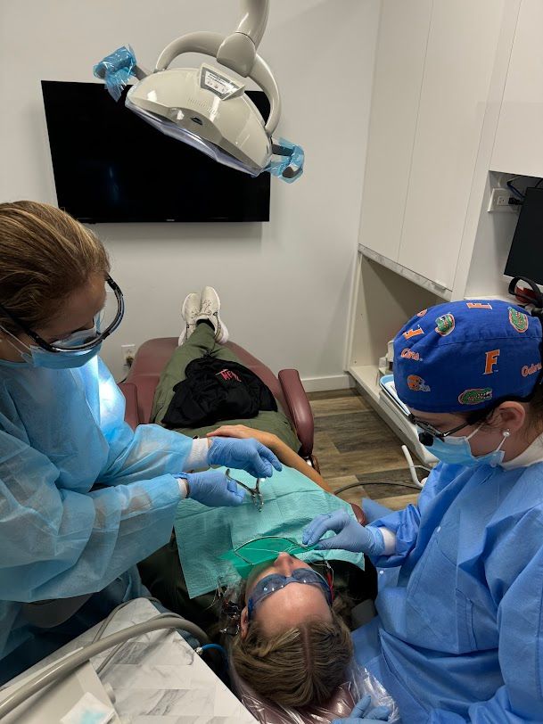 a woman is getting her teeth examined by a dentist wearing a gators hat