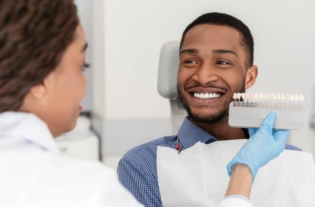 a man is sitting in a dental chair while a dentist examines his teeth .