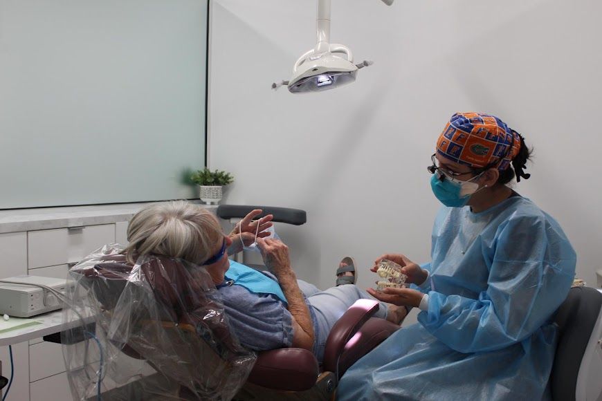 a woman is sitting in a dental chair talking to a dentist .