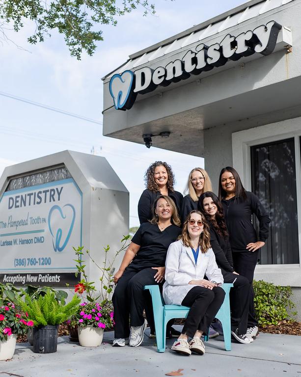 a group of women standing in front of a dentistry sign