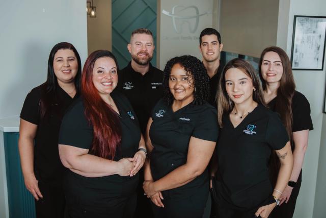 a group of people are posing for a picture in a dental office .