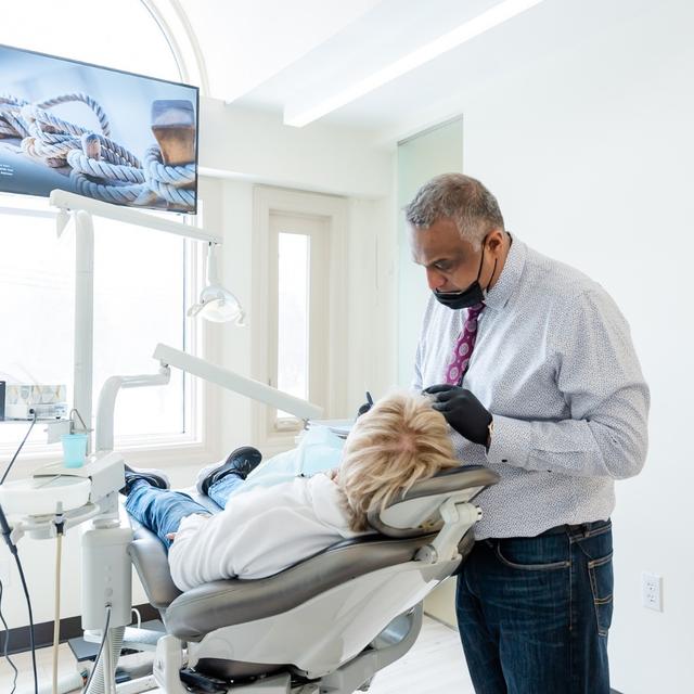 a man is sitting in a dental chair talking to a female dentist .