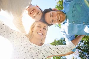 A smiling family of three looks down at the camera.