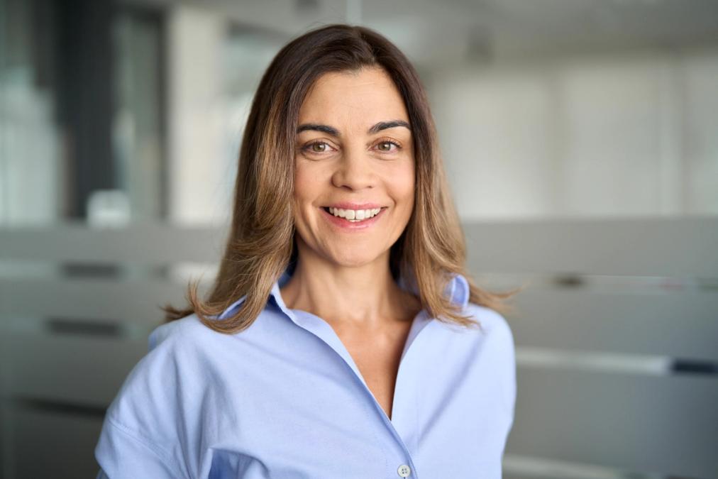A smiling woman with brown hair wearing a light blue shirt.