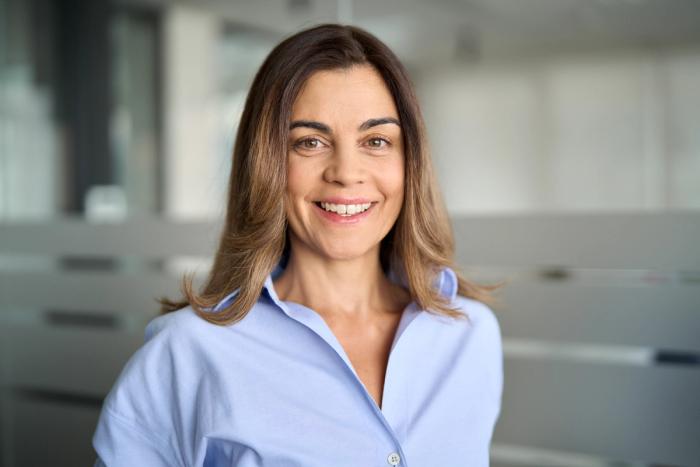 a woman in a blue shirt is smiling and looking at the camera .