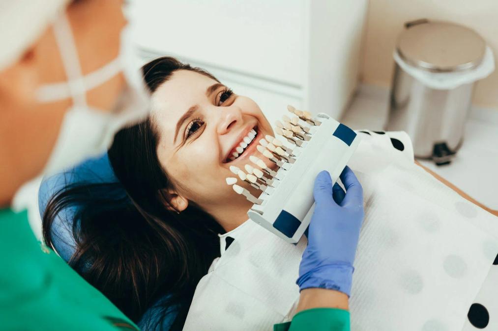a woman is sitting in a dental chair while a dentist examines her teeth .