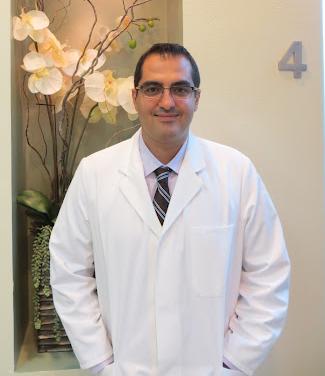 a man in a white lab coat and tie is standing in front of a vase of flowers .