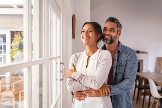 a man and a woman are standing next to each other in front of a window .
