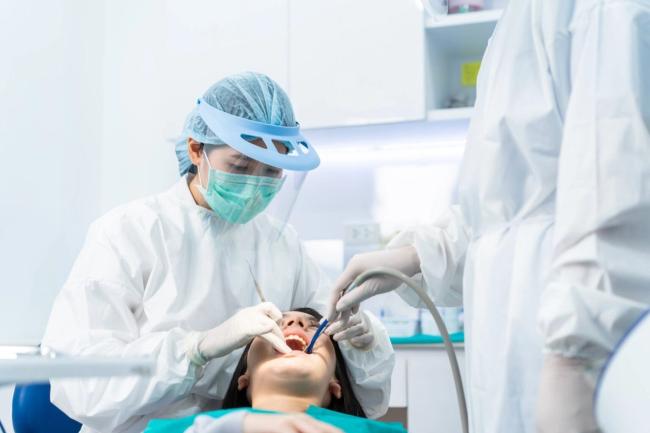 a dentist is examining a patient 's teeth in a dental office .