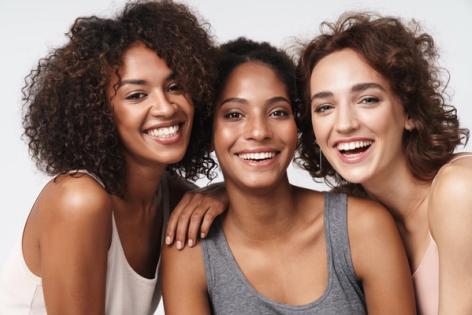 three women are posing for a picture together and smiling .