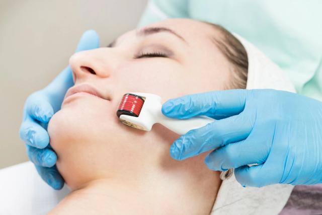 a woman is getting a facial treatment with a roller on her face .