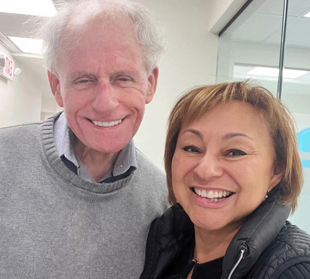 a man and a woman are posing for a picture and smiling for the camera
