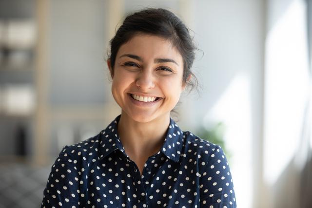 a woman in a polka dot shirt is smiling for the camera .