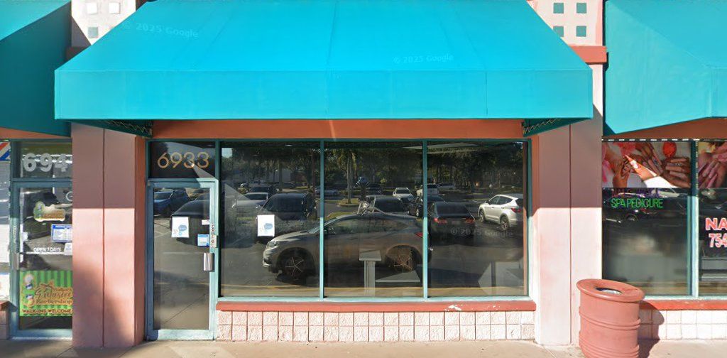 A storefront with a turquoise awning, a large window reflecting a parking lot, and the address 6933.