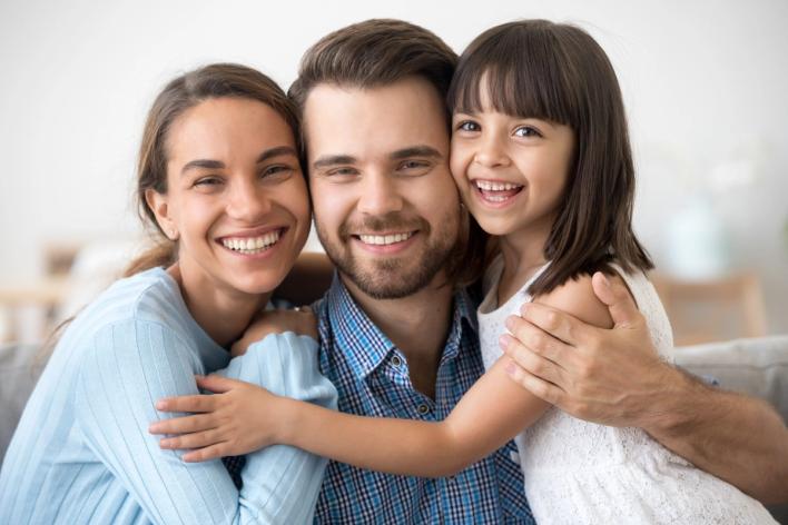 a family is posing for a picture together while sitting on a couch .