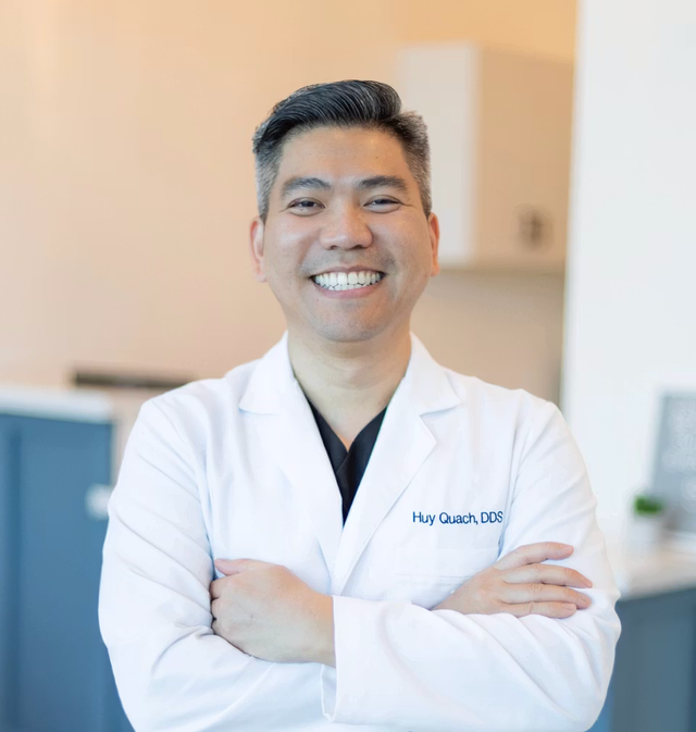 a man in a white coat with the name huy quach on it