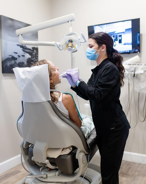 a woman in a dental chair getting her teeth examined by a dentist