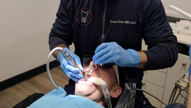 a man is getting his teeth examined by a dentist in a dental office .