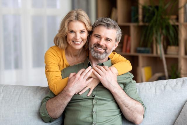 a woman is hugging a man while sitting on a couch .