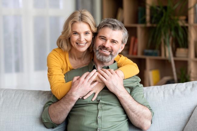 a woman is hugging a man while sitting on a couch .
