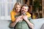 a woman is hugging a man while sitting on a couch .
