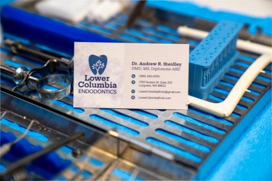Business card for Lower Columbia Endodontics on a tray of dental instruments.