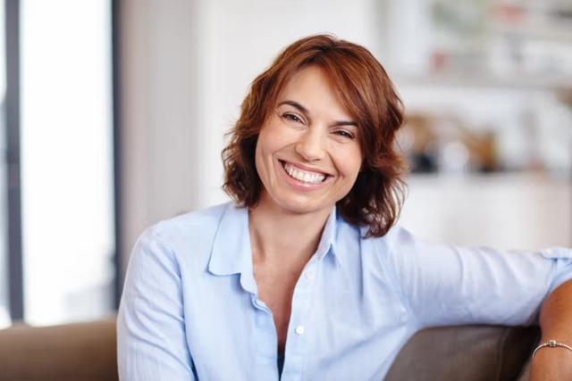 a woman is smiling while sitting on a couch .