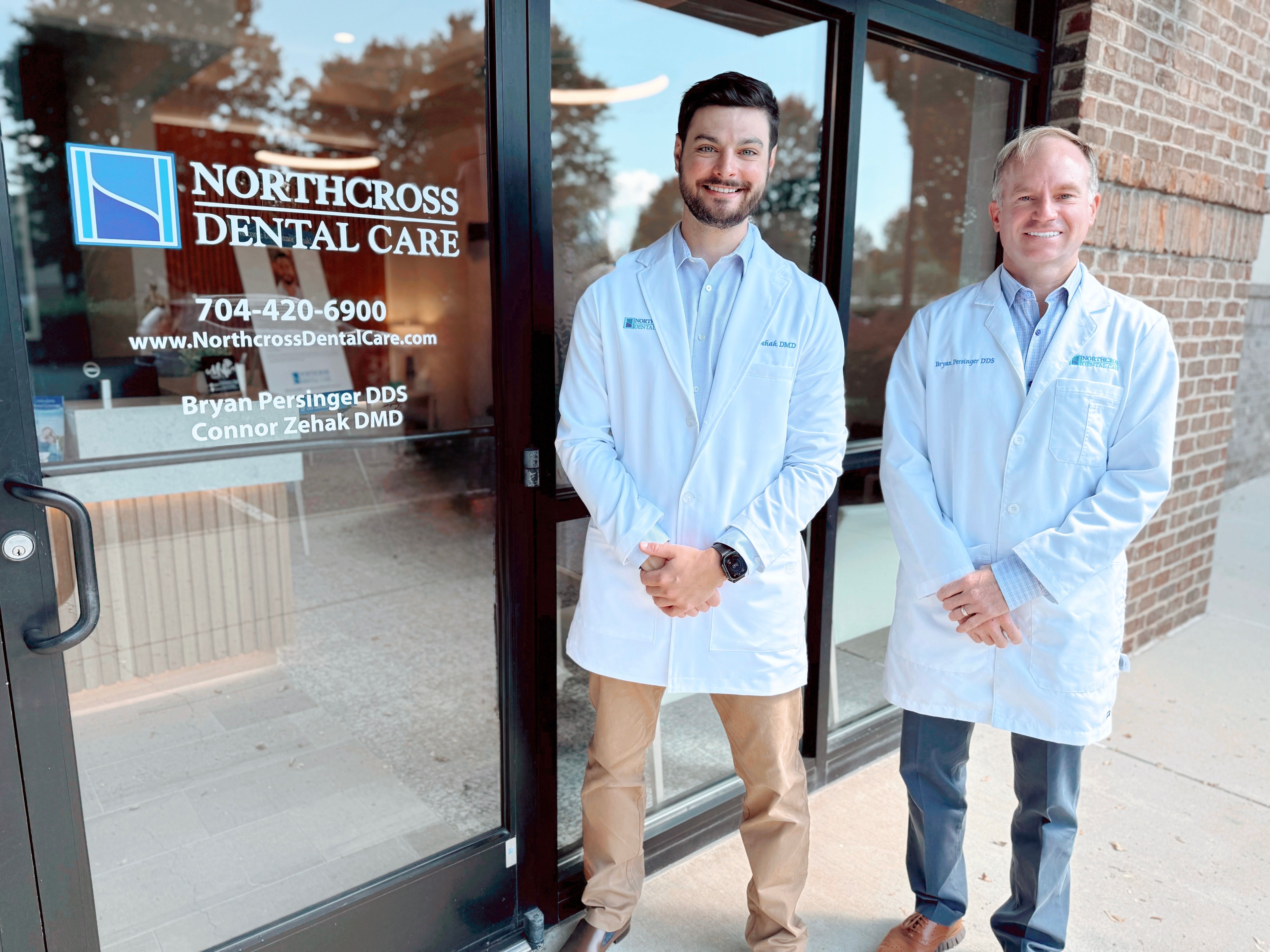 two men in white coats are standing in front of a dental office .
