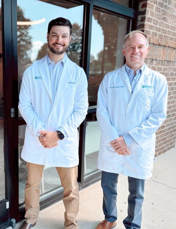 two men in white coats are standing in front of a dental office .