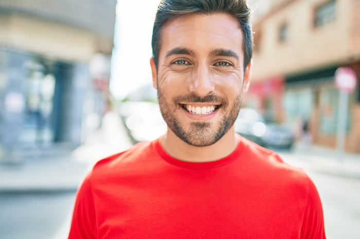 a man in a red shirt smiles for the camera