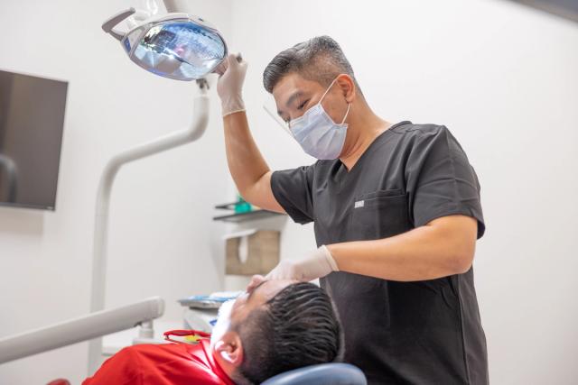 a dentist is examining a patient 's teeth in a dental office .
