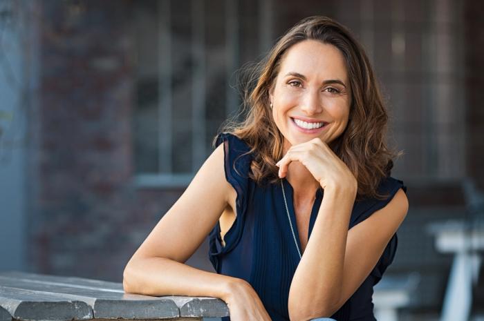 a woman is sitting at a table with her hand on her chin and smiling .