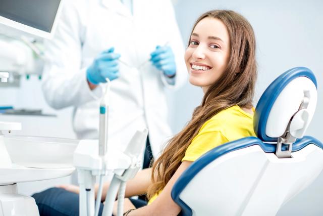 a woman is sitting in a dental chair smiling at the camera .