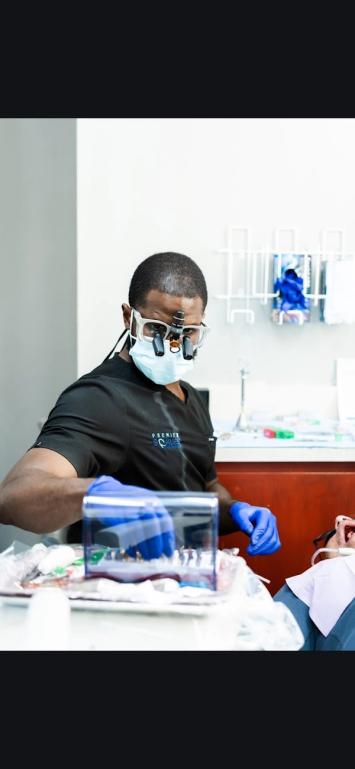 a dentist wearing a mask and glasses is working on a patient 's teeth .