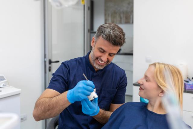 a dentist is examining a woman 's teeth in a dental office .