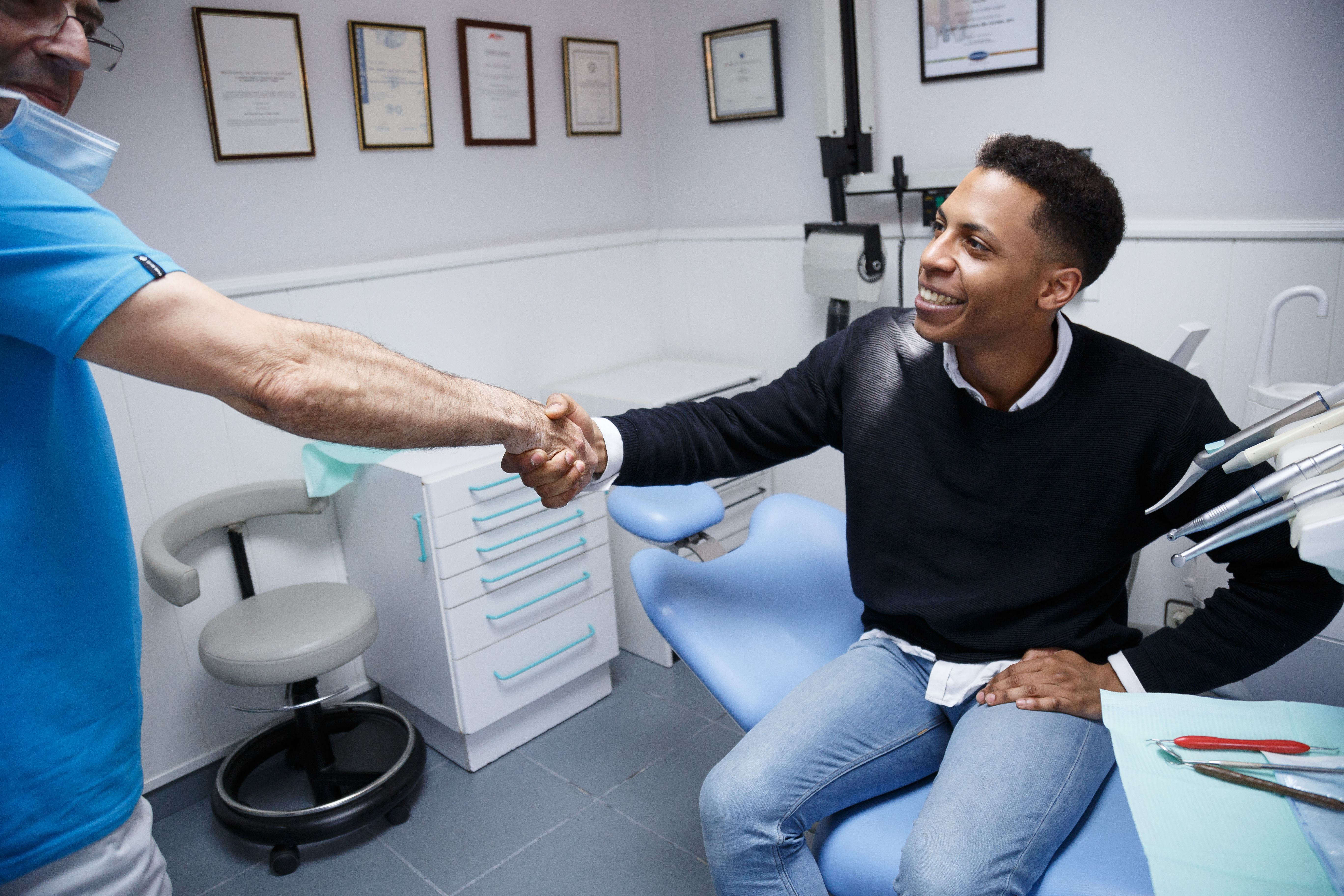 a man is shaking hands with a dentist in a dental office .
