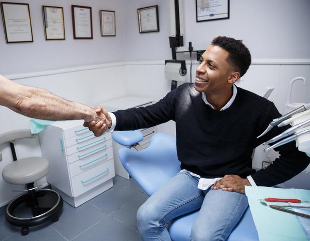 a man is shaking hands with a dentist in a dental office .