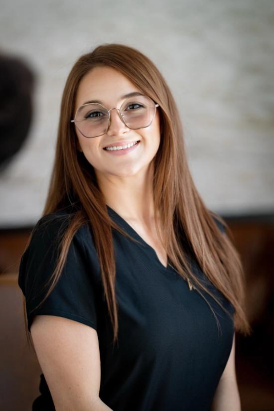 a woman wearing glasses and a black shirt smiles for the camera