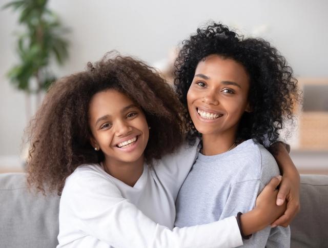 a mother and daughter are hugging each other while sitting on a couch .